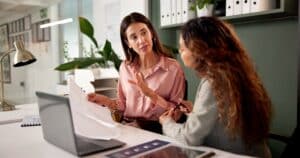 Deux femmes discutent dans un bureau.