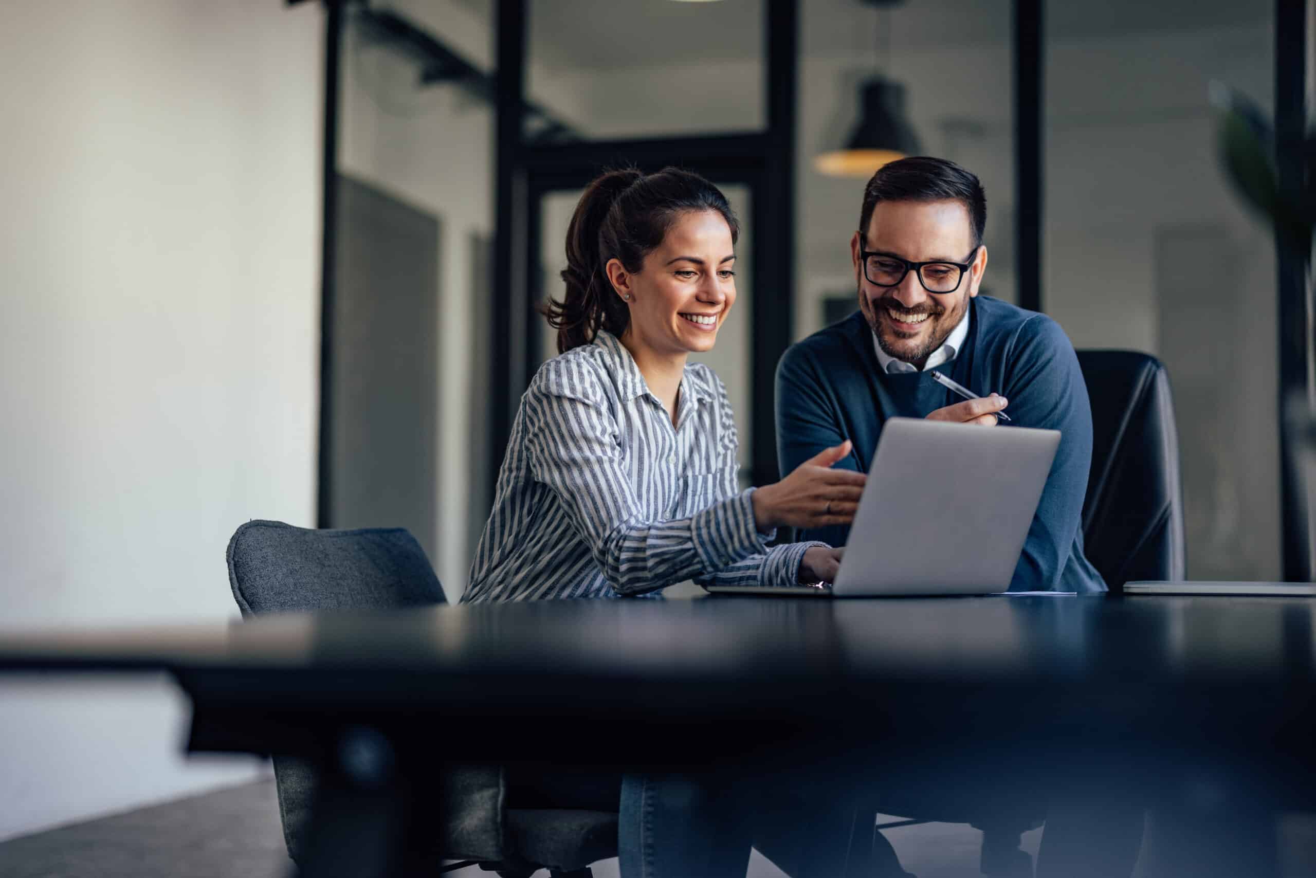 Un consultant échangeant avec un commercial devant un écran affichant un pipeline CRM, ambiance bureau PME